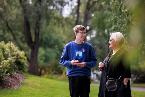 Nuori mies ja häntä vanhempi nainen keskustelevat puistossa.